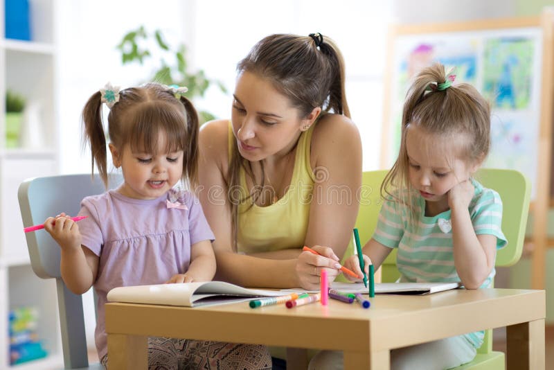Kleuterschoolleraar die kinderen in artclass helpen royalty-vrije stock fotografie Kleuterschoolleraar die kinderen in artclass helpen royalty-vrije stock fotografie