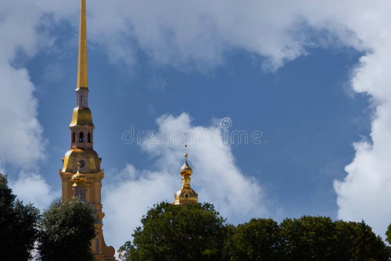 Magnificent view of the buildings of the Peter and Paul Fortress in the center of St. Petersburg, Russia, towers of an ancient Orthodox cathedral with a huge gilded spire, domes and crosses, sky and clouds, European architecture, green plants, cityscape, summer. Magnificent view of the buildings of the Peter and Paul Fortress in the center of St. Petersburg, Russia, towers of an ancient Orthodox cathedral with a huge gilded spire, domes and crosses, sky and clouds, European architecture, green plants, cityscape, summer.