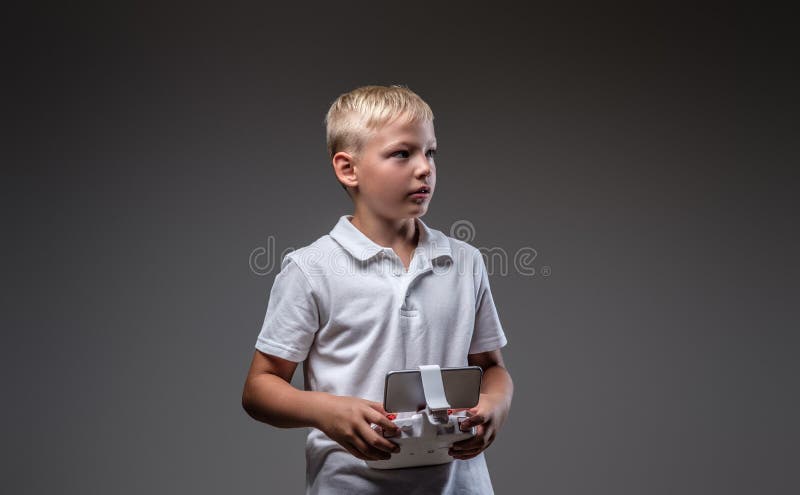 Knap houdt weinig jongensbokser met blondehaar gekleed in een witte t-shirt een quadcoptercontrole ver royalty-vrije stock afbeelding Knap houdt weinig jongensbokser met blondehaar gekleed in een witte t-shirt een quadcoptercontrole ver royalty-vrije stock afbeelding