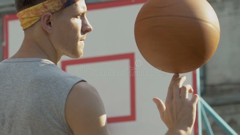 Knap kerel spinnend basketbal op zijn vinger, die professionalisme, sport tonen