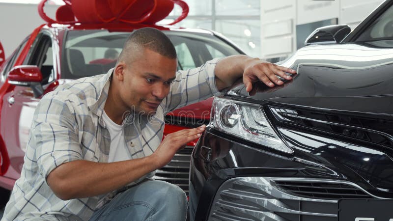 Knappe Afrikaanse mens die duimen tonen terwijl het onderzoeken van nieuwe auto