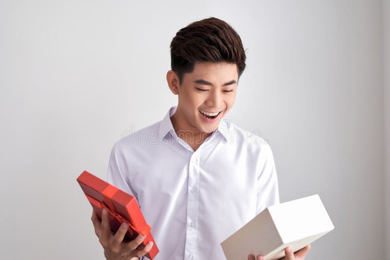 Knappe baard jonge mens die en een bruine giftdoos, g glimlachen openen stock fotografie Knappe baard jonge mens die en een bruine giftdoos, g glimlachen openen stock fotografie
