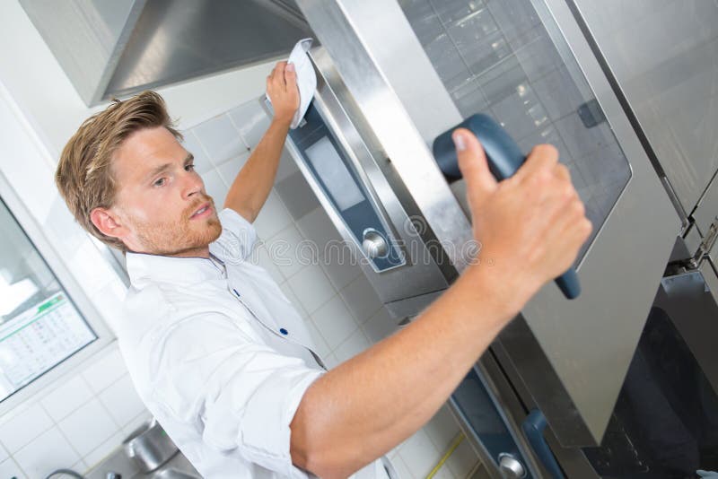 Knappe chef-kok hulp schoonmakende keuken met vod stock afbeeldingen Knappe chef-kok hulp schoonmakende keuken met vod stock afbeeldingen