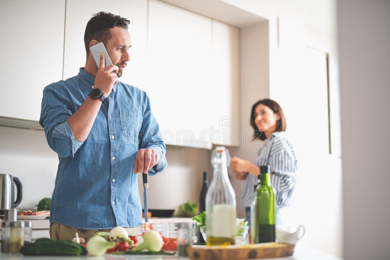 Knappe gebaarde heer die op cellphone in keuken spreken stock foto Knappe gebaarde heer die op cellphone in keuken spreken stock foto