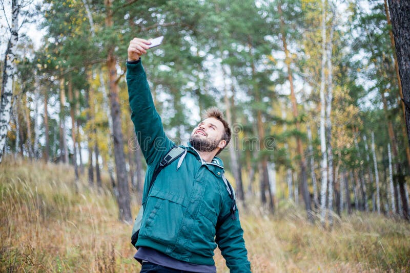 Knappe gebaarde mannelijke toerist die een selfie in een bos nemen stock foto Knappe gebaarde mannelijke toerist die een selfie in een bos nemen stock foto