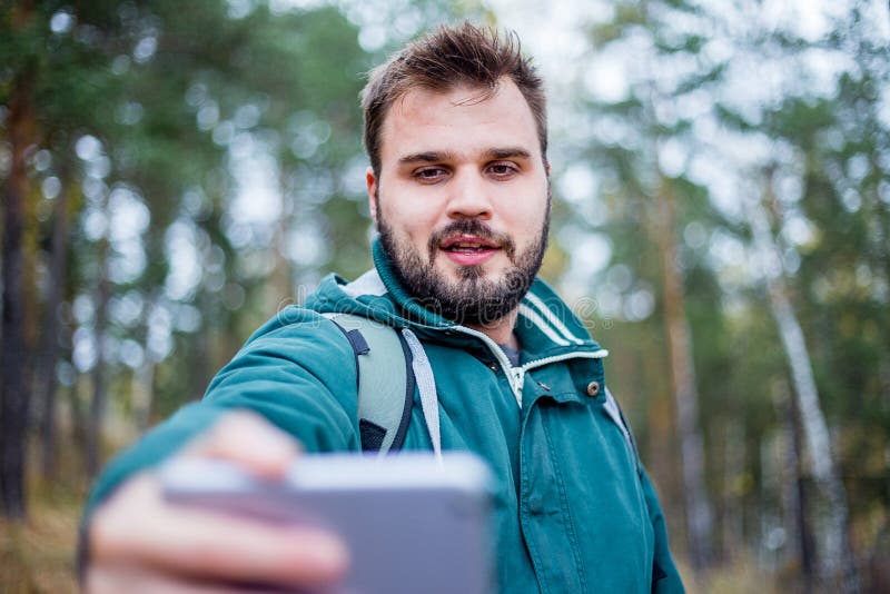 Knappe gebaarde mannelijke toerist die een selfie in een bos nemen royalty-vrije stock afbeelding Knappe gebaarde mannelijke toerist die een selfie in een bos nemen royalty-vrije stock afbeelding