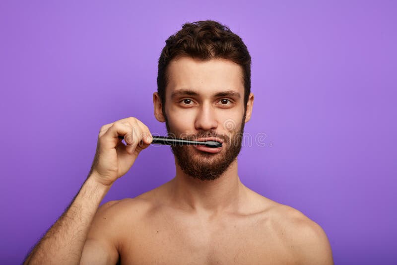 Knappe gebaarde mens die met tandenborstel in zijn mond de camera bekijken stock foto Knappe gebaarde mens die met tandenborstel in zijn mond de camera bekijken stock foto