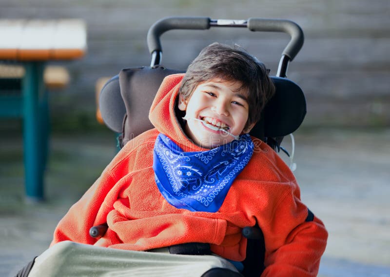 Knappe, gelukkige biracial acht éénjarigenjongen die in wheelchai glimlachen