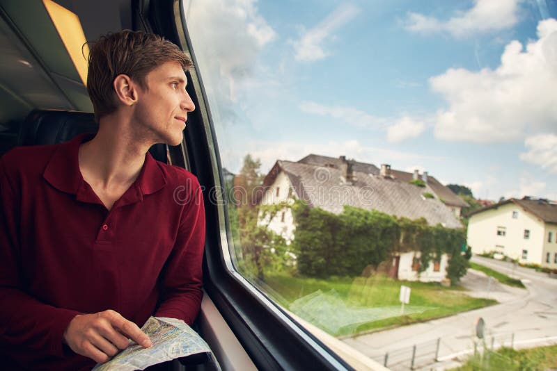 Knappe jonge mens die een kaart op de trein gebruiken reiziger op de weg royalty-vrije stock afbeeldingen Knappe jonge mens die een kaart op de trein gebruiken reiziger op de weg royalty-vrije stock afbeeldingen