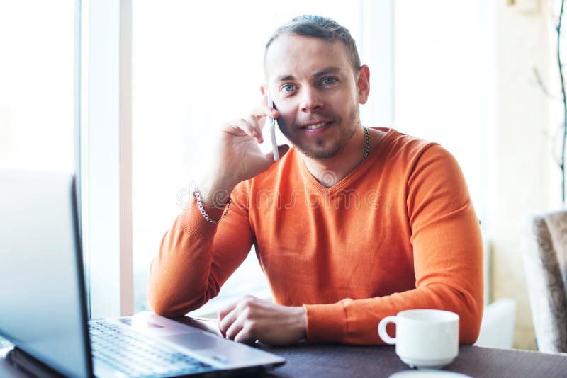 Knappe jonge mens die met notitieboekje, die aan de telefoon, het glimlachen werken, die camera bekijken, terwijl het genieten va stock fotografie Knappe jonge mens die met notitieboekje, die aan de telefoon, het glimlachen werken, die camera bekijken, terwijl het genieten va stock fotografie