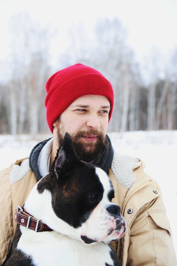 Knappe jonge mens met zijn bokserhond in openlucht stock fotografie Knappe jonge mens met zijn bokserhond in openlucht stock fotografie