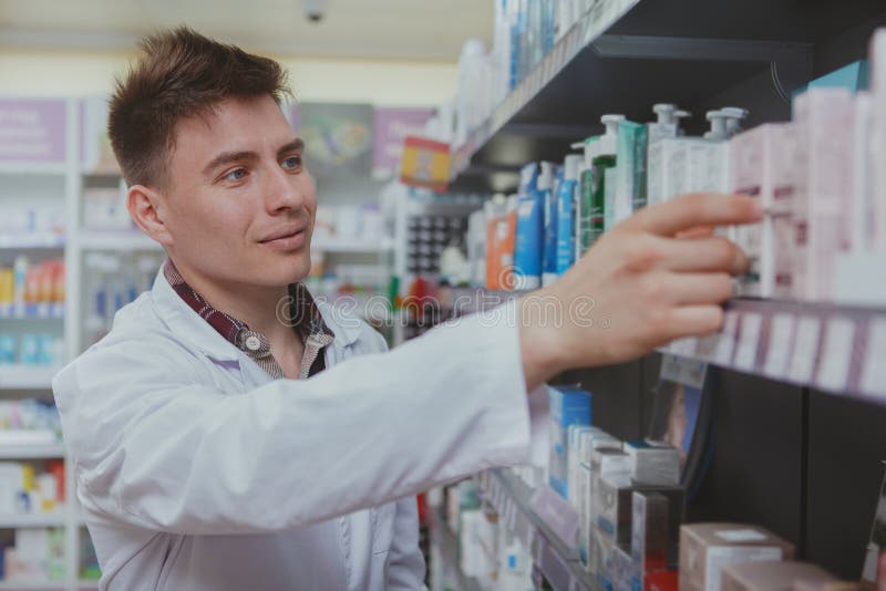 Knappe mannelijke apotheker die bij zijn drogisterij werken royalty-vrije stock afbeelding Knappe mannelijke apotheker die bij zijn drogisterij werken royalty-vrije stock afbeelding