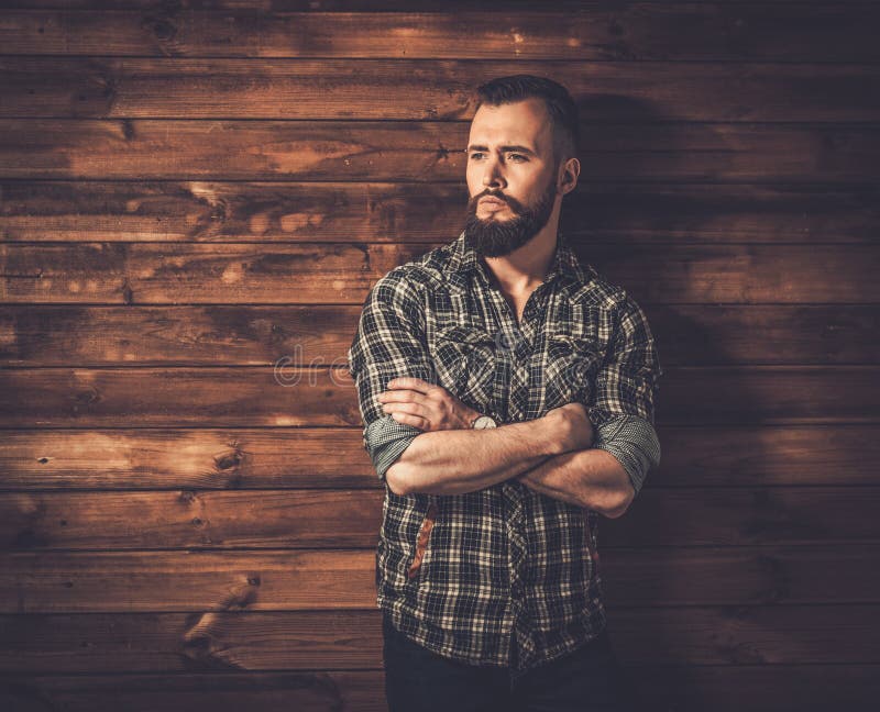 Handsome man wearing checkered shirt in wooden rural house interior. Handsome man wearing checkered shirt in wooden rural house interior