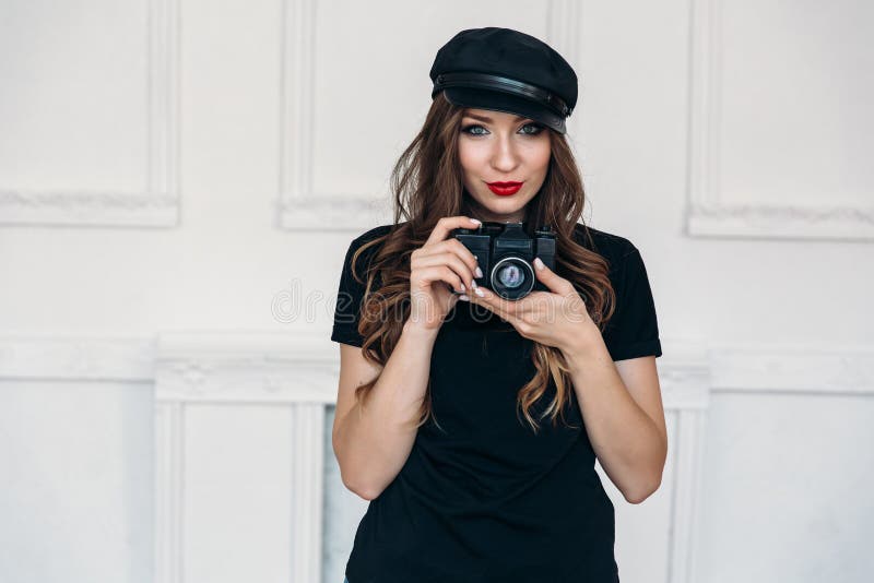 Knappe modieuze meisjesfotograaf, die een zwarte T-shirt zonder drukken, en een GLB dragen, die haar lippen met rood kleuren royalty-vrije stock foto's Knappe modieuze meisjesfotograaf, die een zwarte T-shirt zonder drukken, en een GLB dragen, die haar lippen met rood kleuren royalty-vrije stock foto's