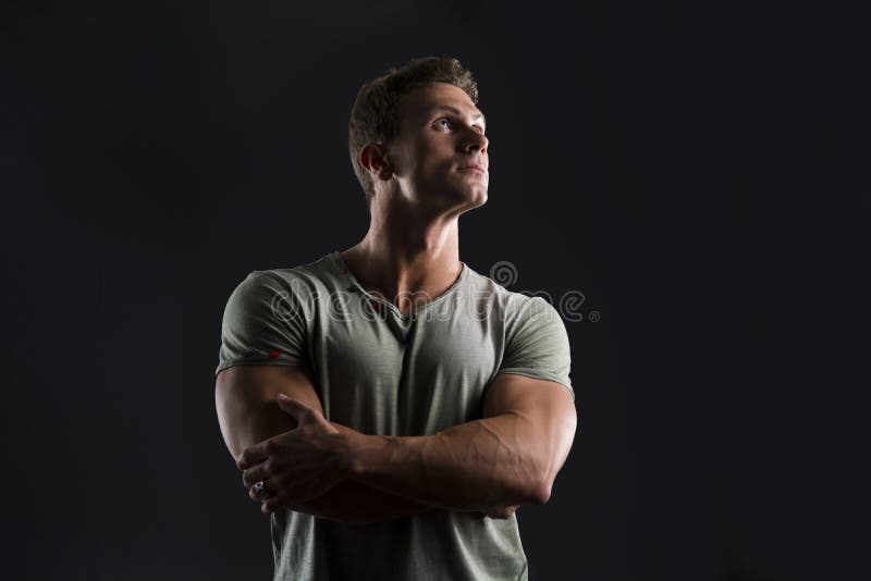 Knappe spier geschikte jonge mens die op donkere achtergrond omhoog kijken stock afbeelding Knappe spier geschikte jonge mens die op donkere achtergrond omhoog kijken stock afbeelding