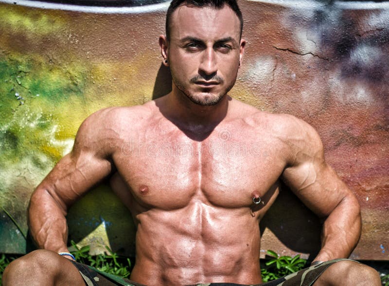 Knappe, spierbodybuilderzitting tegen kleurrijke muur stock afbeeldingen Knappe, spierbodybuilderzitting tegen kleurrijke muur stock afbeeldingen