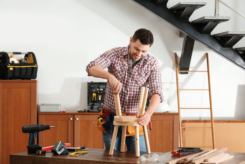 Knappe werkende mens die houten kruk herstellen royalty-vrije stock fotografie Knappe werkende mens die houten kruk herstellen royalty-vrije stock fotografie