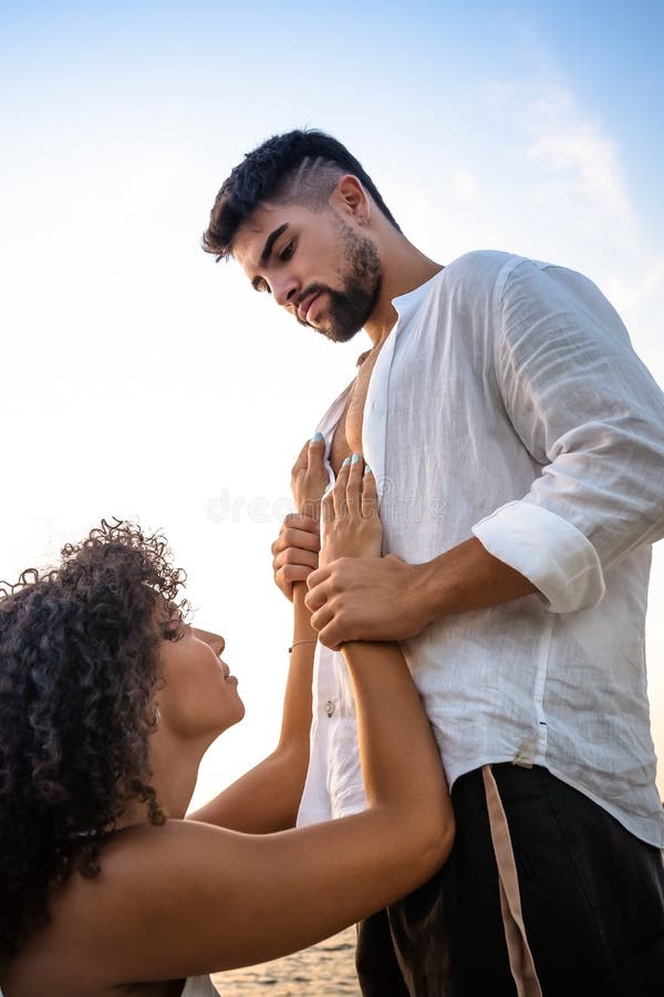 Kneeling Submissive Woman Begs Her Man by Holding His Hands on His Massive Chest, but he Squeezes Her Wrists As a Sign of Stock Photo