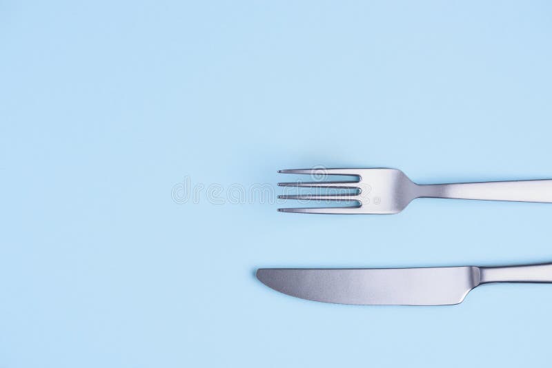 Knife and fork on blue pastel background stock images