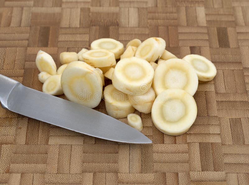 Knife with parsnip slices on a wood cutting board royalty free stock photography