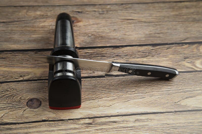 Knife Sharpener.a Man Sharpens Kitchen Knives for the House Stock Photo