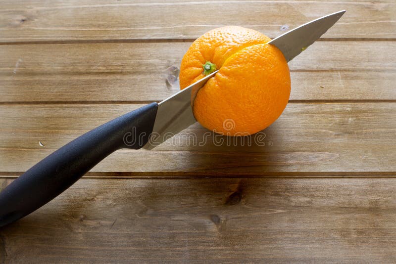 Knife slicing through an orange of the kitchen table before breakfast.