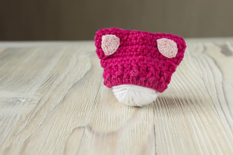 Knitted crochet small pink hat. Women`s hat for feminists march protest. Creative craft work stock image Knitted crochet small pink hat. Women`s hat for feminists march protest. Creative craft work stock image
