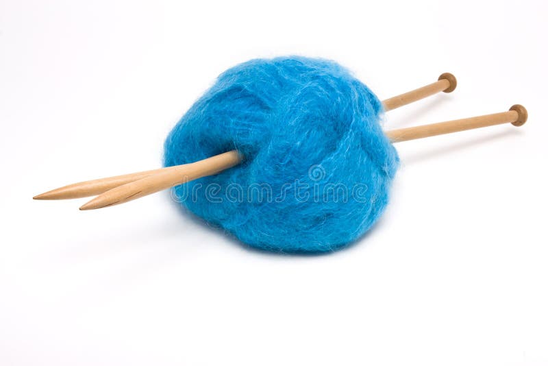 A large ball of blue mohair wool pierced with large wooden knitting needles against white.