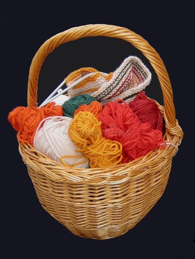 Multicolored yarn balls in a straw basket on a wooden table Stock