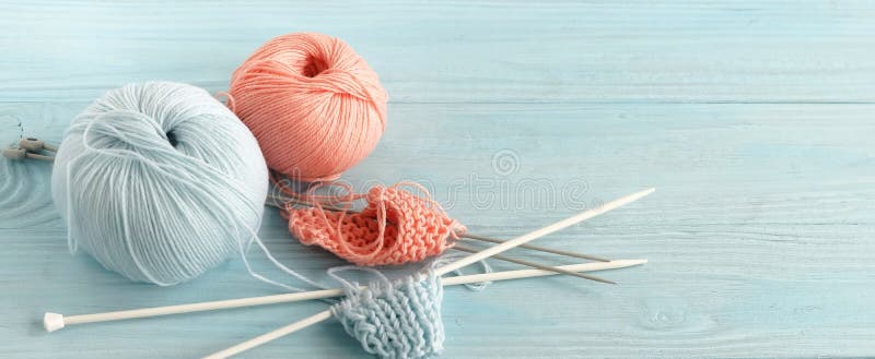Knitting wool and knitting needles in pastel blue and pink colors on blue wooden background. top view.copy space