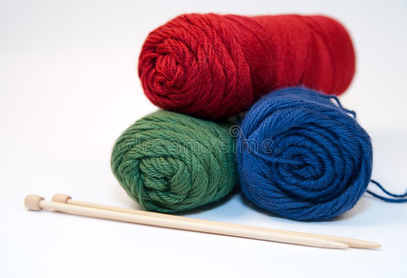 Three primary colored yarn skeins with bamboo knitting needles on a white background. Three primary colored yarn skeins with bamboo knitting needles on a white background.