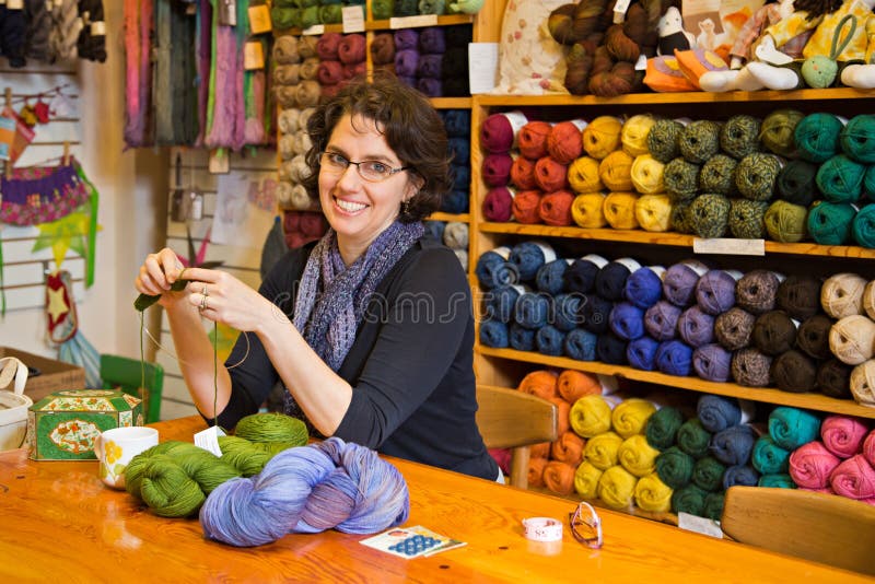 Krásná brunetka pletení na pracovní stůl v příze shop.