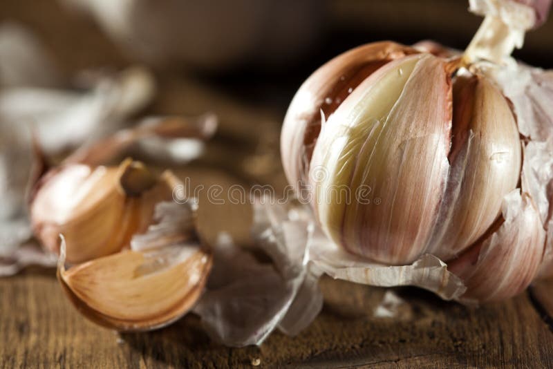 A ball of garlic with some cloves lying next to it on wood. A ball of garlic with some cloves lying next to it on wood