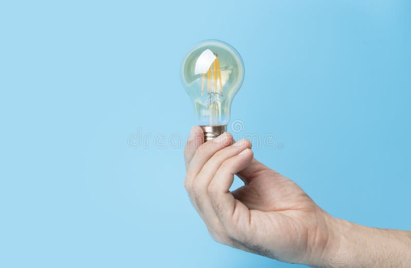 Knowledge and idea concept. Light bulb with light in hand on a blank blue background. Brain, wisdom, knowledge and stock photo