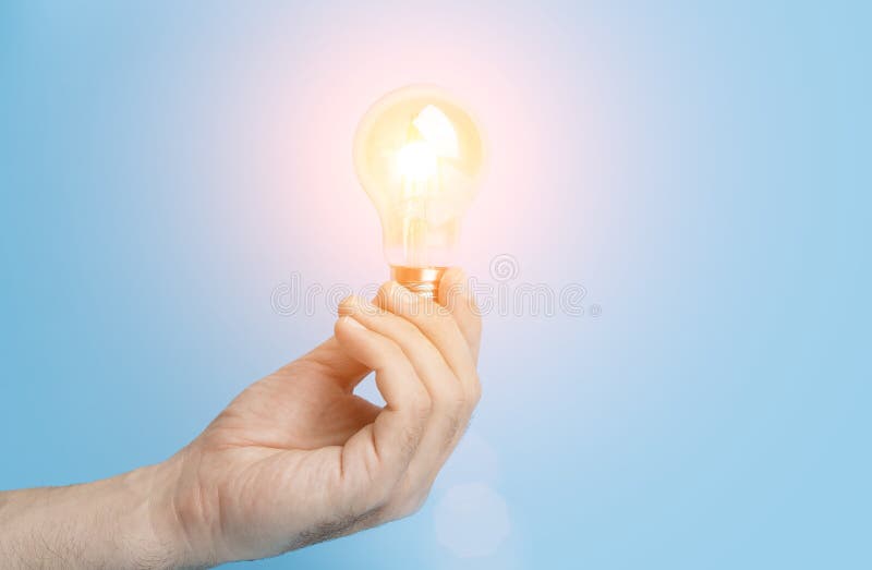 Knowledge and idea concept. Light bulb with light in hand on a blank blue background. Brain, wisdom, knowledge and royalty free stock photo