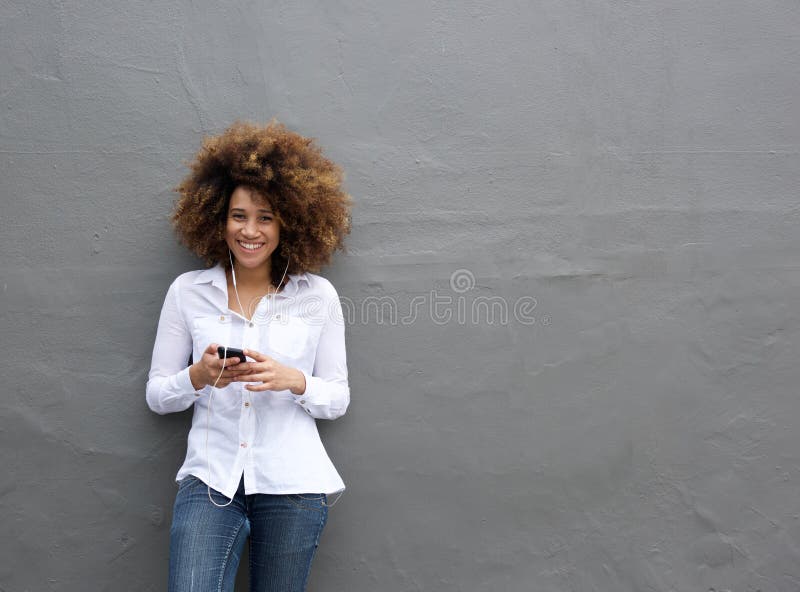 Portrait of young african american woman with afro listening to music on smart phone. Portrait of young african american woman with afro listening to music on smart phone