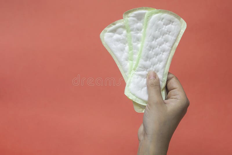 Woman`s hands holding feminine hygiene pads. Hands of female hold menstrual pads or sanitary napkins for women. Pink background. Woman`s hands holding feminine hygiene pads. Hands of female hold menstrual pads or sanitary napkins for women. Pink background