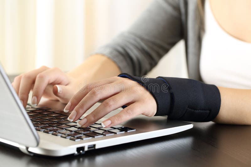 Close up of a woman hands with injured wrist working on line with a laptop on a desk in a house interior. Close up of a woman hands with injured wrist working on line with a laptop on a desk in a house interior