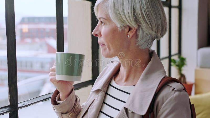 Kobieta biznesowa pijąca kawę lub myśląca przez okno w nowoczesnym biurowym studio reklamowym lub agencji marketingowej. menedżer zdjęcie wideo