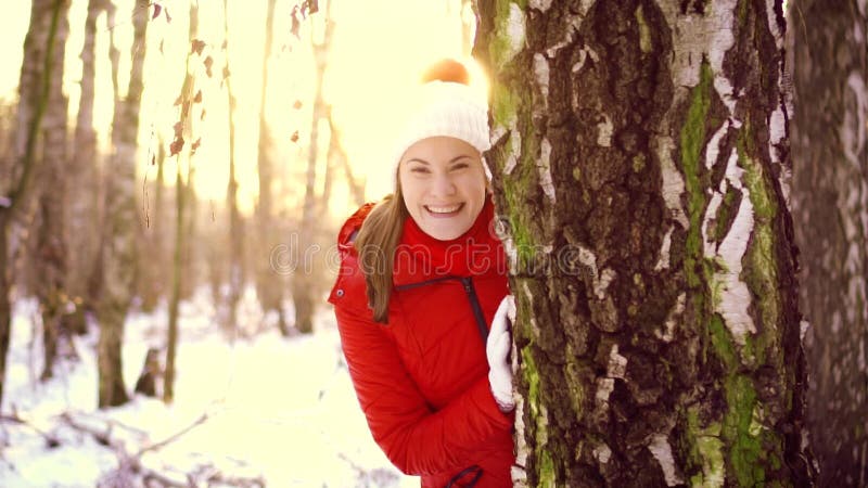 Kobieta cieszy się zima dzień outdoors Szczęśliwa dziewczyna chuje za dużym drzewem w zima parku w zwolnionym tempie