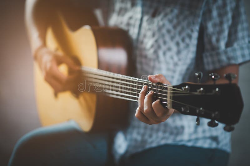 Kobieta grająca na gitarze akustycznej siedząca w parku publicznym w odprężonym. kobieta ćwicząca na gitarze pod drzewem szczęśliw fotografia royalty free