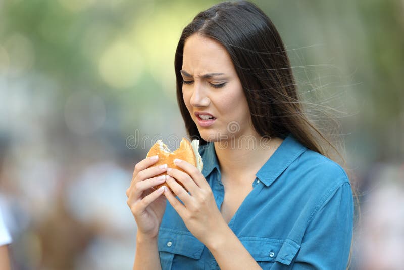Kobieta je hamburger z złym smakiem