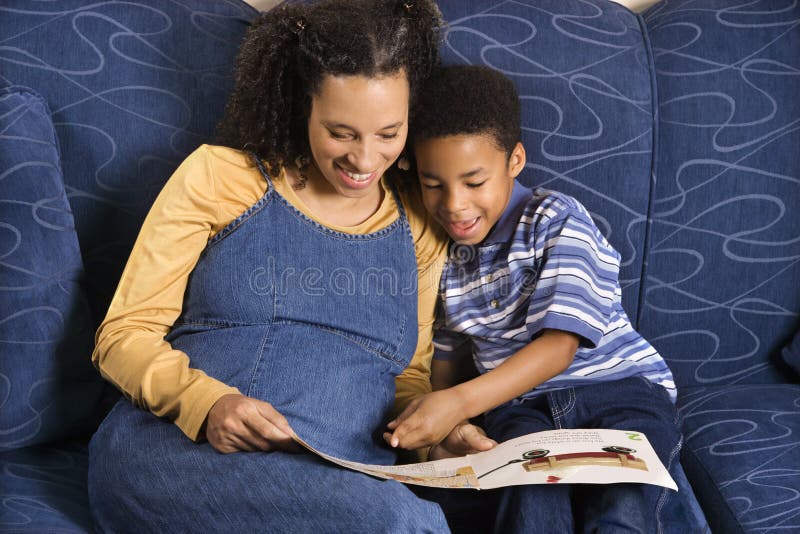 A mid adult woman sitting on a couch reading a book to her young son. Horizontal shot. A mid adult woman sitting on a couch reading a book to her young son. Horizontal shot.