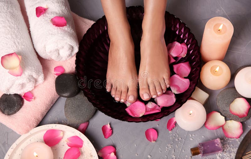 Kobieta moczy jej cieki w pucharze z wod? i r??anymi p?atkami na pod?odze w spa zdjęcia stock Kobieta moczy jej cieki w pucharze z wod? i r??anymi p?atkami na pod?odze w spa zdjęcia stock