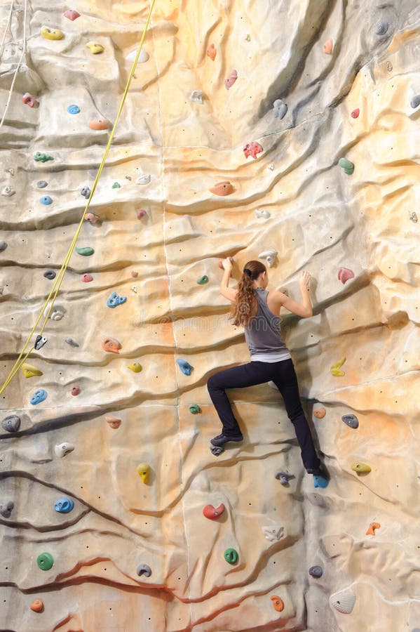 Active young woman on rock wall in sport center. Active young woman on rock wall in sport center