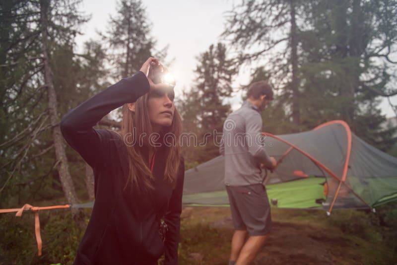 Kobieta obraca dalej headlamp latarkę blisko wiszącego namiotowego campingu Grupa przyjaciele zaludnia lato przygody podróż wewną zdjęcia royalty free Kobieta obraca dalej headlamp latarkę blisko wiszącego namiotowego campingu Grupa przyjaciele zaludnia lato przygody podróż wewną zdjęcia royalty free
