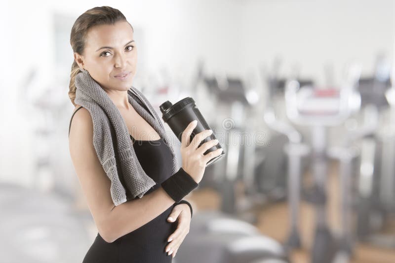 Woman resting with a towel around her neck after a fitness workout, in a gym. Woman resting with a towel around her neck after a fitness workout, in a gym