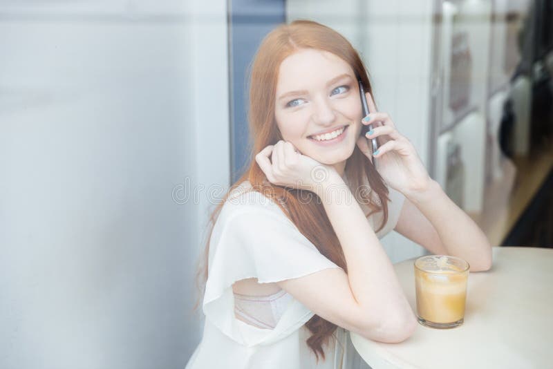 Kobieta opowiada na telefonie komórkowym i pije kawę w kawiarni zdjęcia royalty free Kobieta opowiada na telefonie komórkowym i pije kawę w kawiarni zdjęcia royalty free