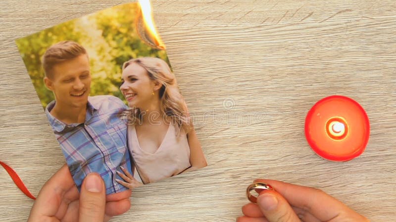 Kobieta pali rodzinną fotografię i trzyma pierścionek zaręczynowego, rozwód i zdradę
