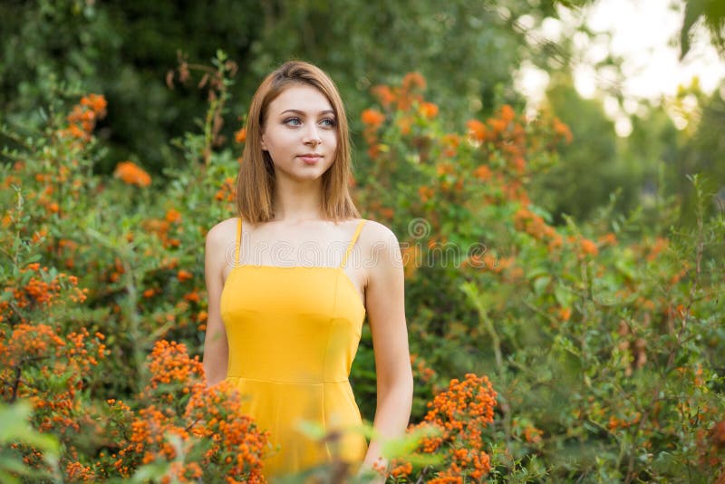 Kobieta patrząca na boczne marzenia w pobliżu pomarańczowych krzaków jagodowych w ogrodzie fotografia stock Kobieta patrząca na boczne marzenia w pobliżu pomarańczowych krzaków jagodowych w ogrodzie fotografia stock